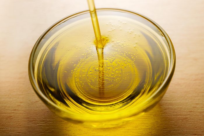 Olive Oil being poured into a small glass dish on a wooden table