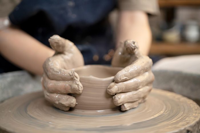hands creating a clay pot on a pottery wheel