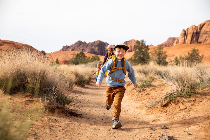 A young boy smiles while running down a trail.
