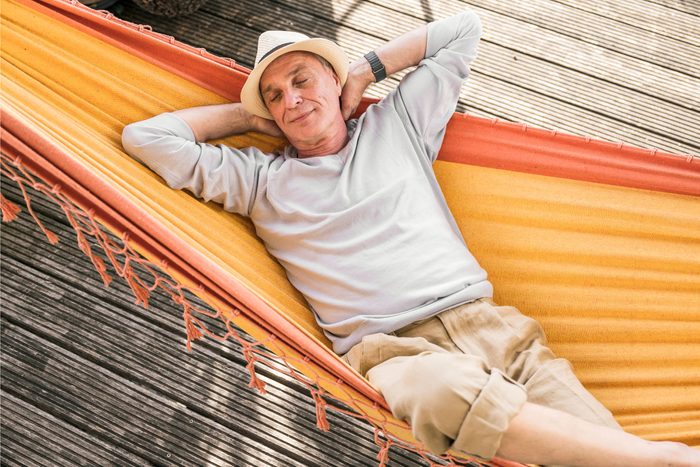 senior Man with hands behind head sleeping in hammock