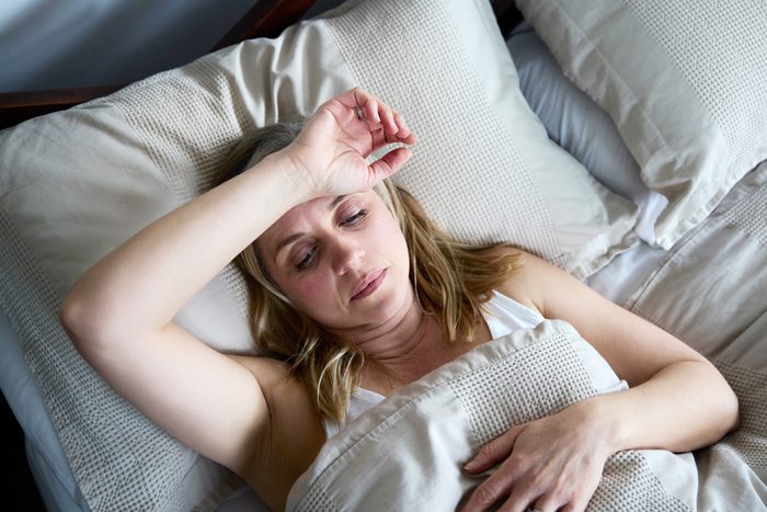 woman in bed with her arm resting on forehead