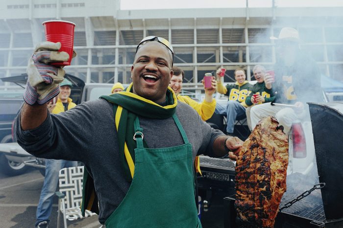 Men having barbeque at tailgate party in stadium parking lot