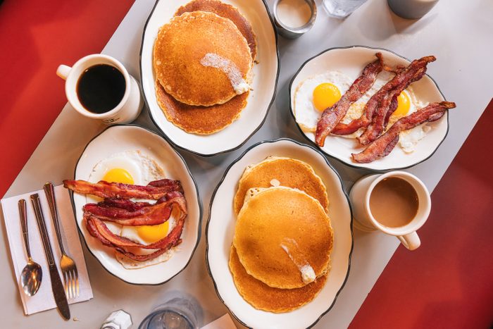 Overhead of American Breakfast At The Diner With Fried Eggs, Bacon And Pancakes and Coffee