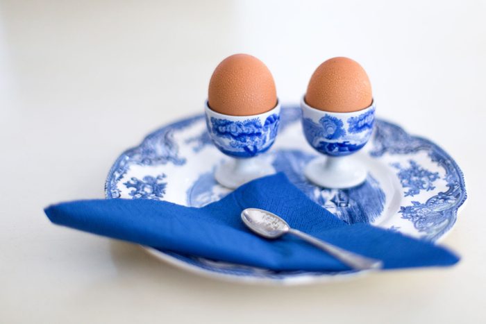 Boiled eggs in spode egg cups on a spode plate with a blue serviette.