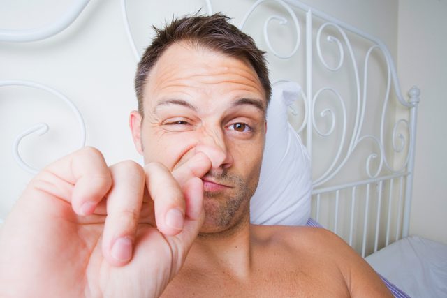 Man picking his nose in bed.