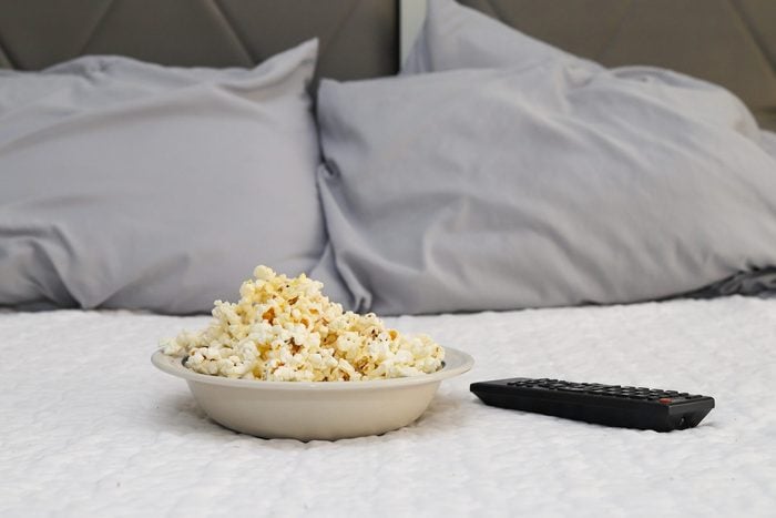 A bowl of popcorn on a bed