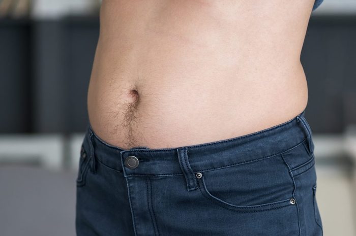 Man in blue jeans at home, diet and overeating concept