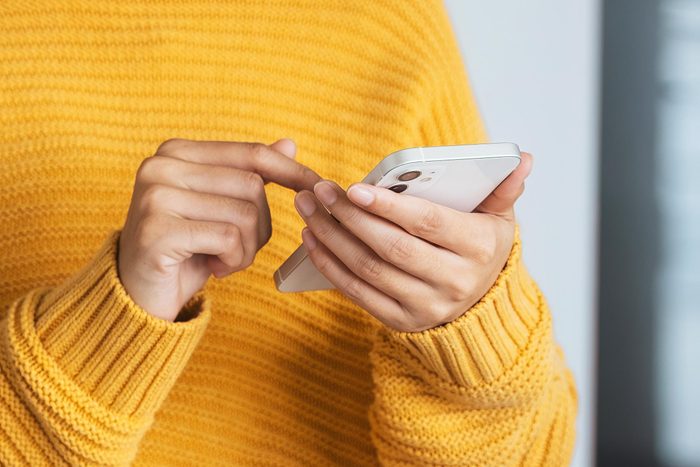 person with yellow sweater holding an iphone while waiting for the doctor