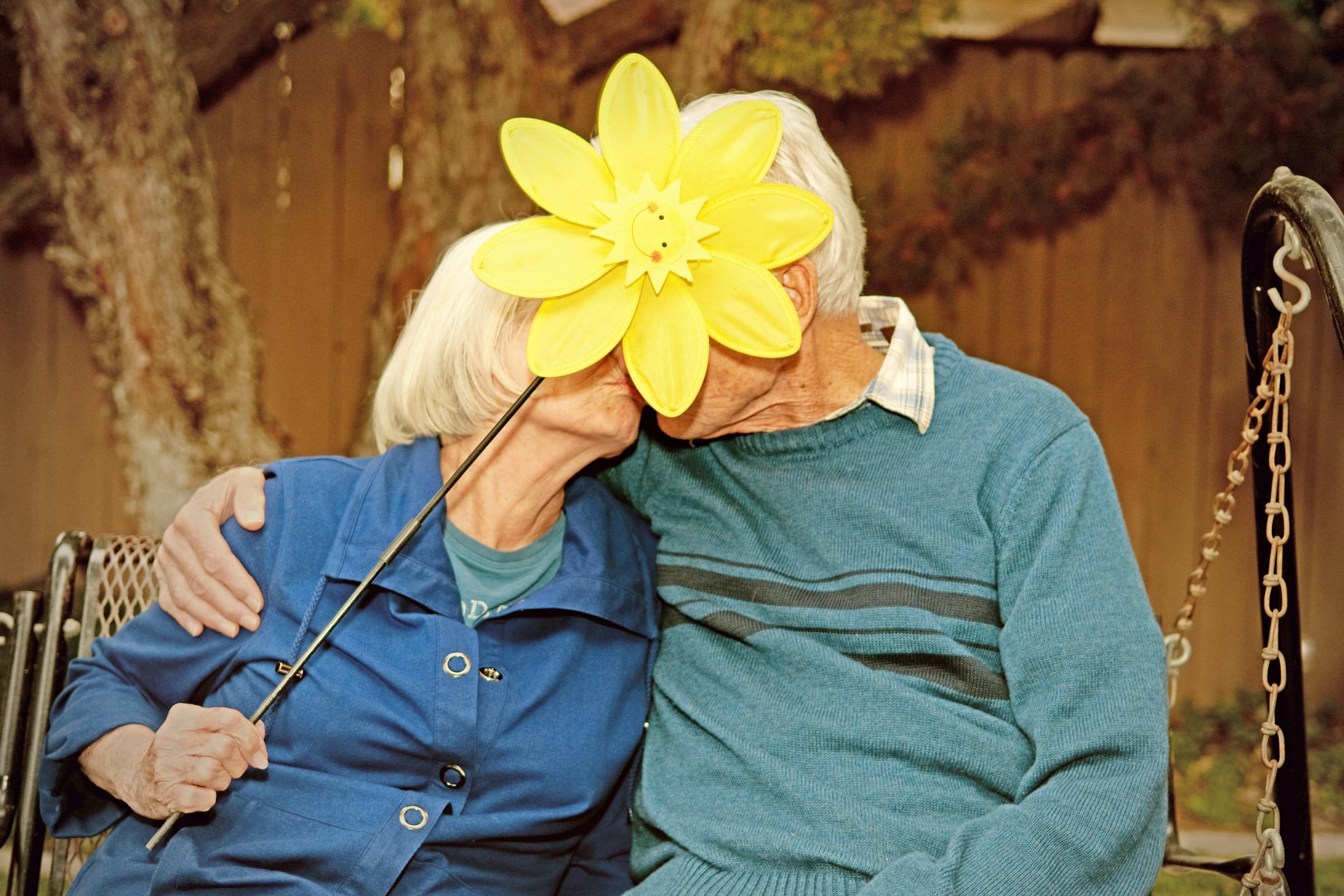 old couple kissing behind a sunflower