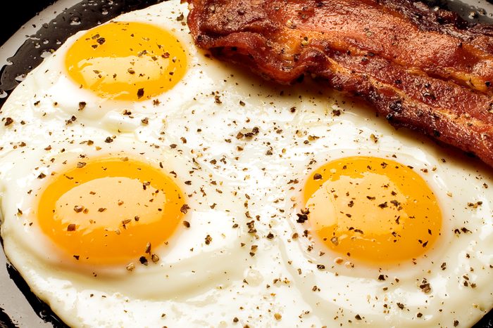 three sunny side up eggs with a side of bacon