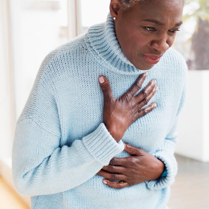woman holding her chest experiencing heart attack symptoms