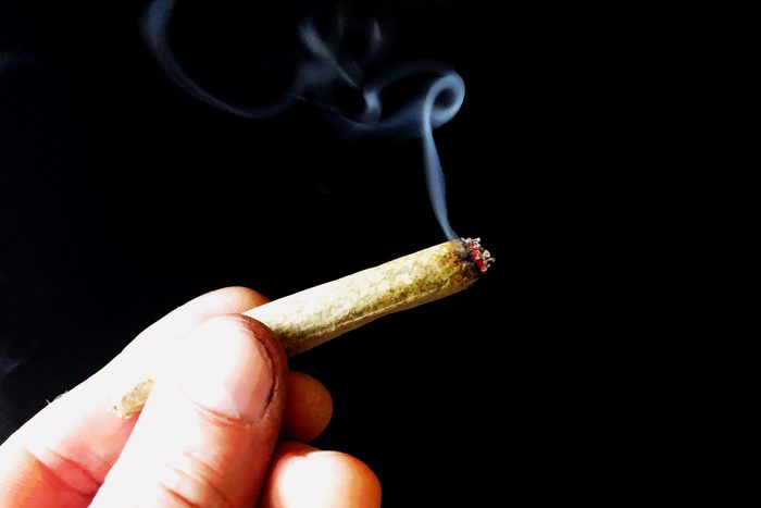 hand holding a joint against a black background