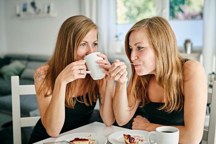 idnetical twins having breakfast and coffee together