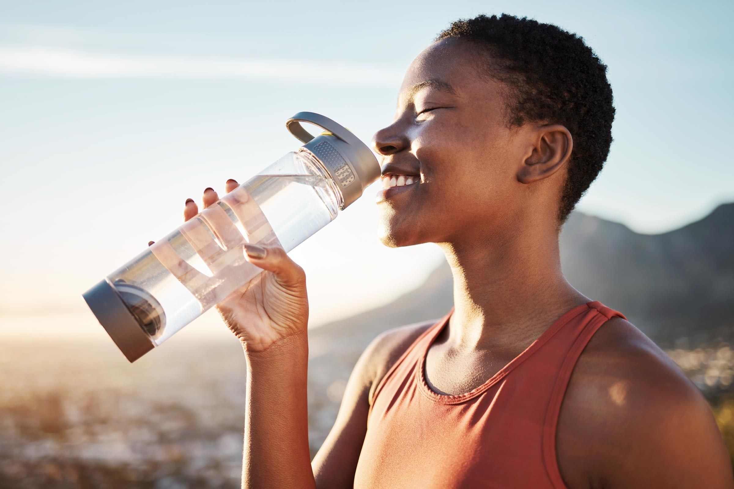 woman drinking water outside after a run