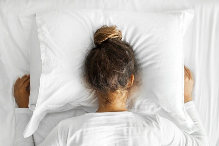 woman face down on a white pillow looking depressed