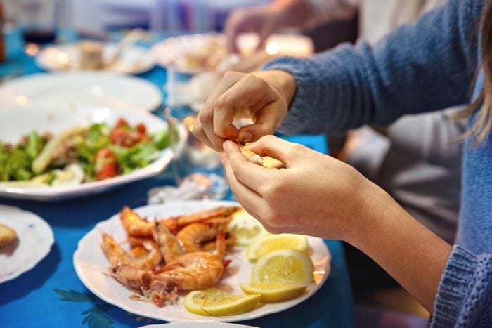 Close-up of hands peeling prawns on the family table