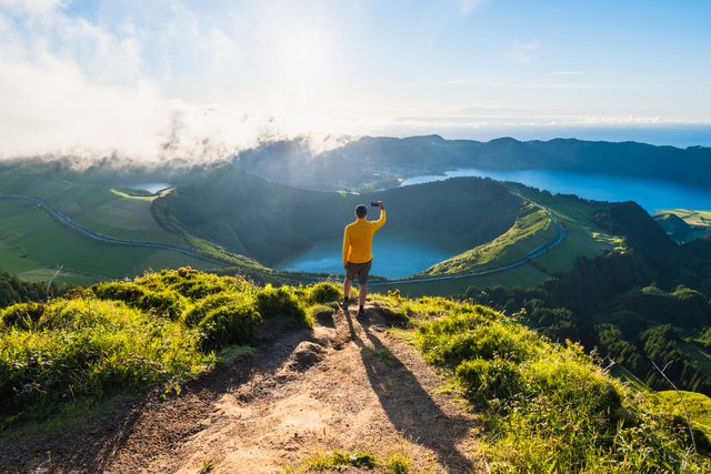 Man on top of a mountain photographing volcanoes in Sao Miguel, Azores