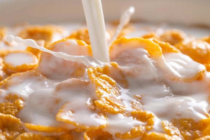 milk being poured on a bowl of cornflake cereal