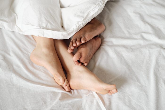 Bare feet of multiracial females lying in bed