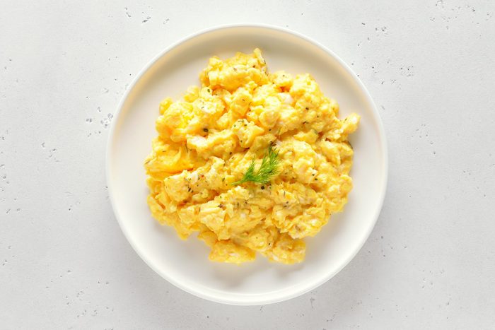 Scrambled eggs on plate over white stone background