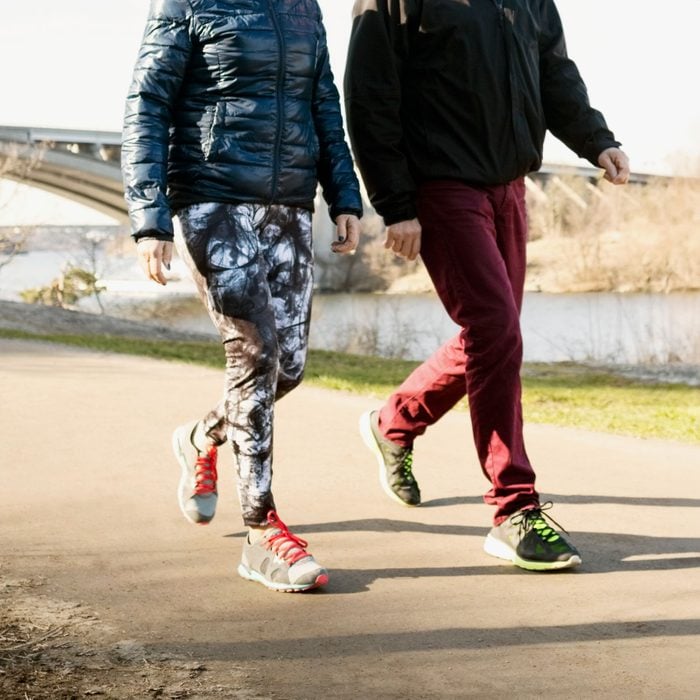 Low section of man and woman in sportswear walking on road