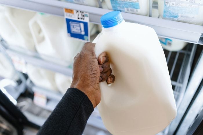 hand holding a gallon container of milk at the supermarket