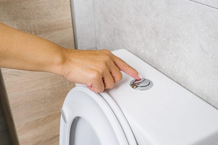 Woman hand flushing toilet for cleaning