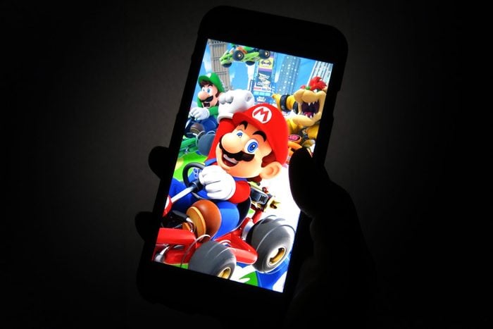 Mario Kart Tour screen on a phone in a hand with dark moody background