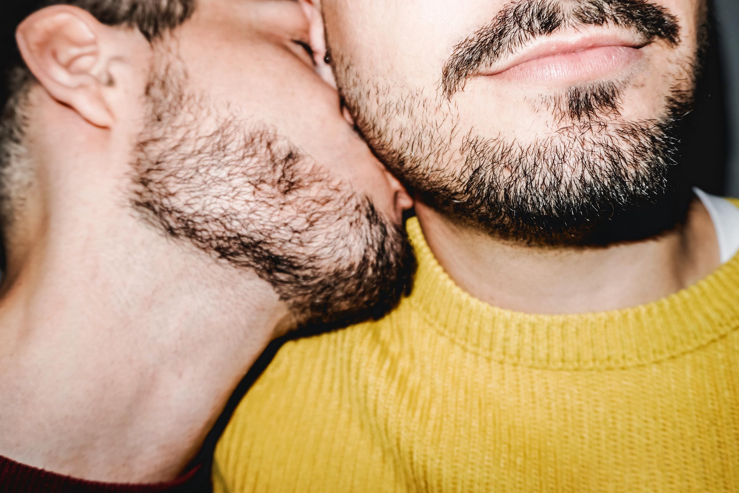 man kissing another man's neck